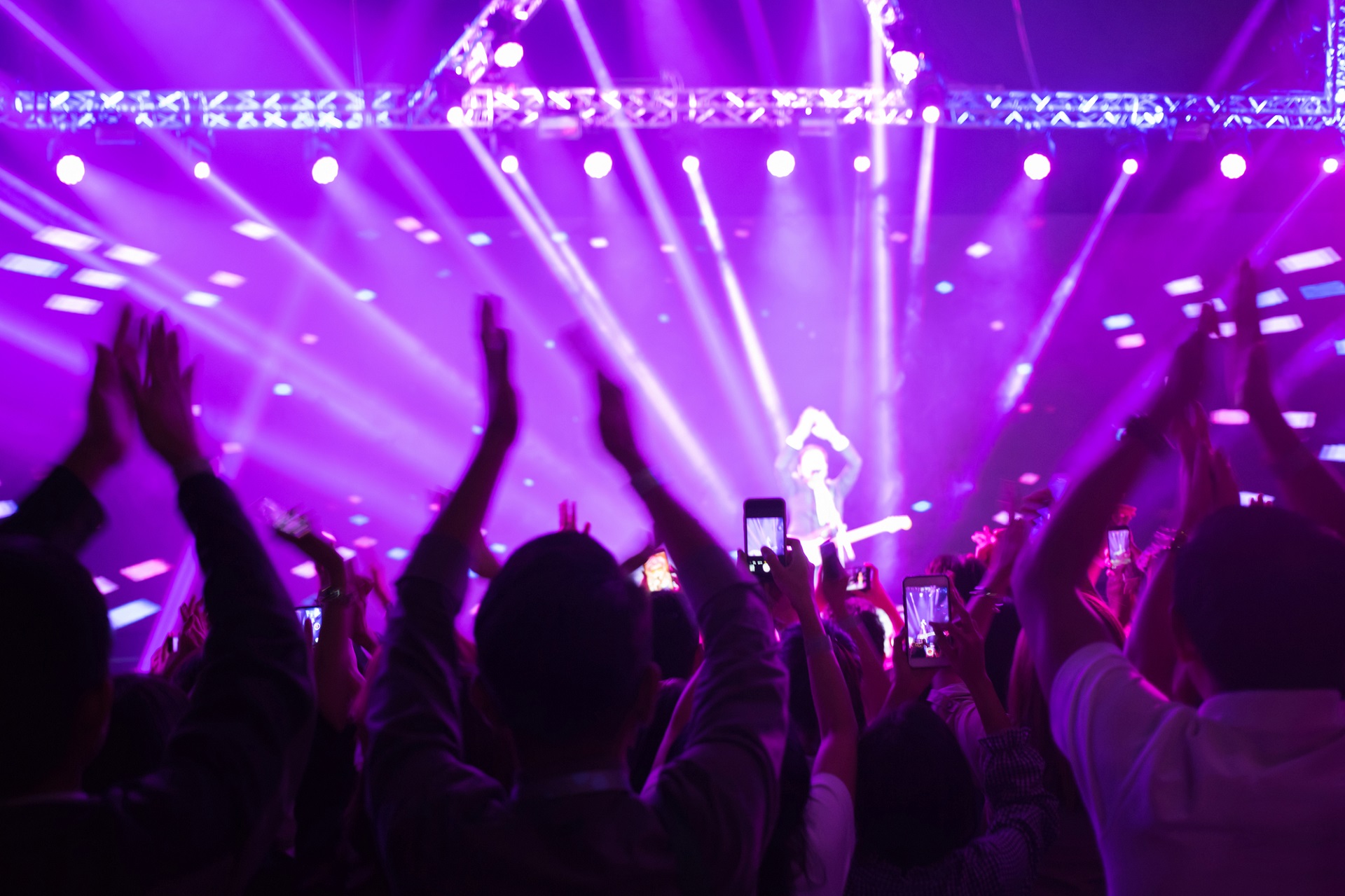 Crowd enjoying concert, happy people jumping, large group celebrating new year holiday, party background fun concept, blurred